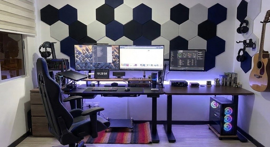 Gaming room with hexagon wall panels, multiple monitors, and RGB glow.
Bold geometric backdrop gives the setup a quirky, creative identity.